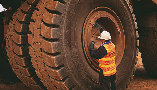 man with a white helmet checking a huge tire