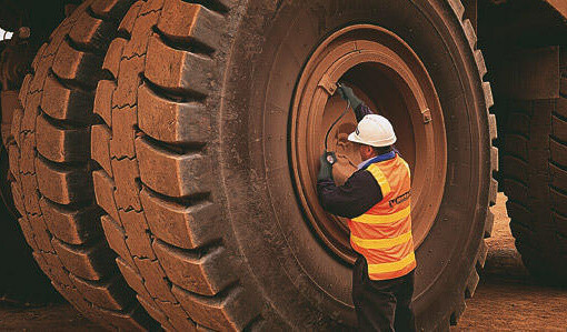man with a white helmet checking a huge tire