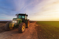 Tracteur vert dans un champ au lever de soleil