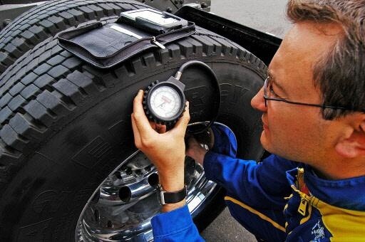 Un homme vérifie la pression d'un pneu poids lourd