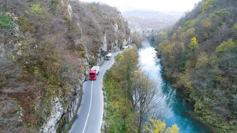 Poids lourd circulant sur une route de montage longeant une rivière