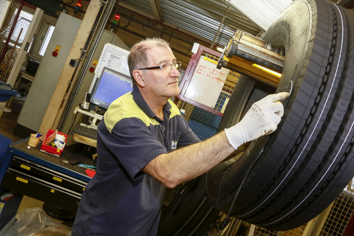 os50870 Un homme en usine vérifie la qualité d'un pneu