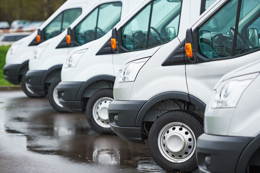 Des fourgons de livraisons garés en ligne sur un parking d'une société de transport