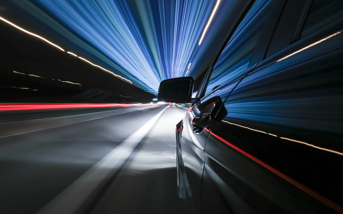 car going fast on a road by night