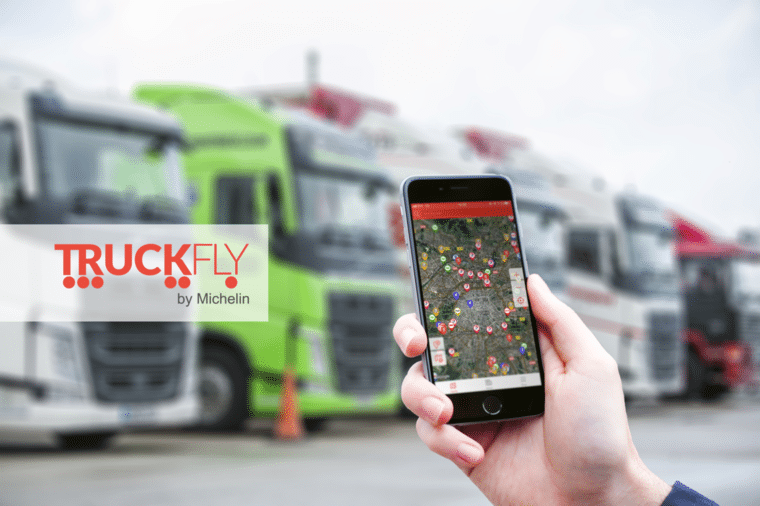 Smartphone montrant l'app Truckfly sur un parking de camions