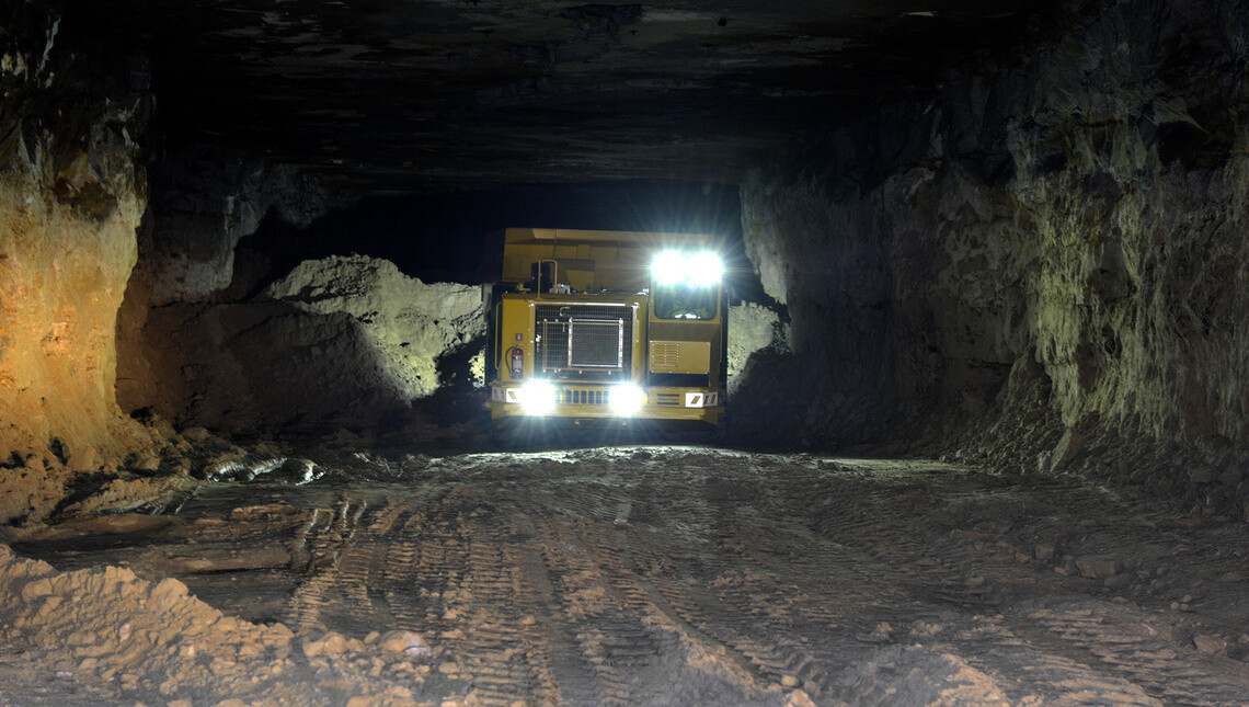 A mining vehicle shown underground with its lights on.