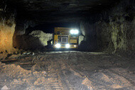 A mining vehicle shown underground with its lights on.