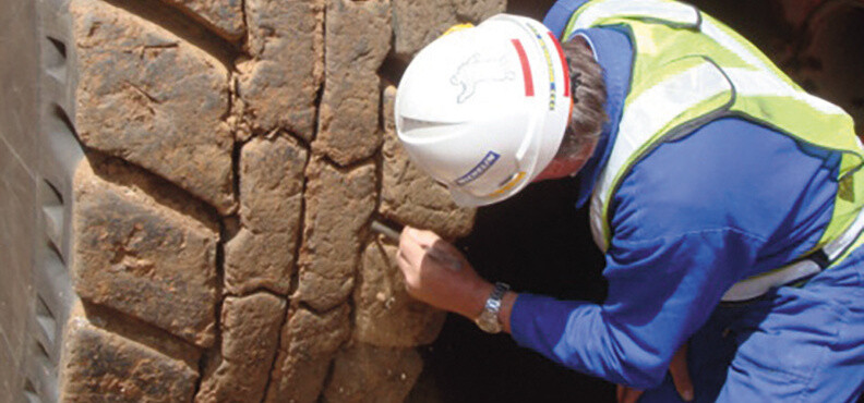 A man inspecting a large mining tyre.