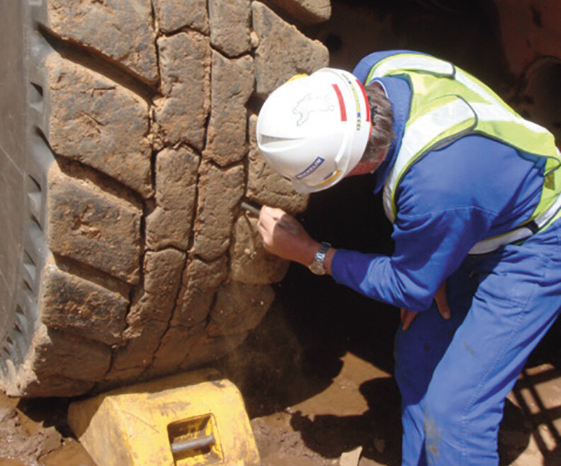 Worker inspecting the tread of a large off-road equipment tire