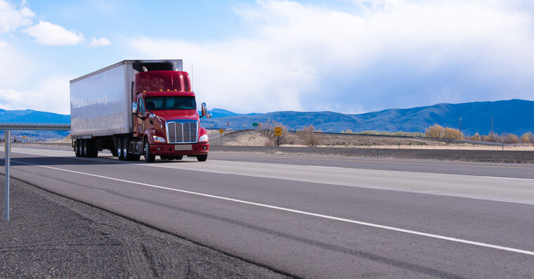 Big rig American bonnet powerful red semi truck with refrigerated semi trailer with refrigerator unit for cooling trailer inside space transporting commercial cargo on flat road in Utah