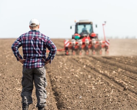 Farmer standing in a field near agricultural equipment