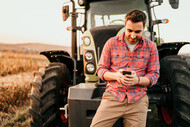 Men with cellphone using the  agropressure app close to the tractor