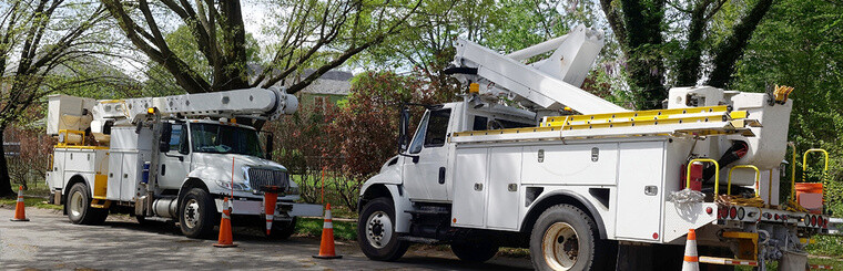 Parked telecommunications utility vehicle on shaded neighborhood street.