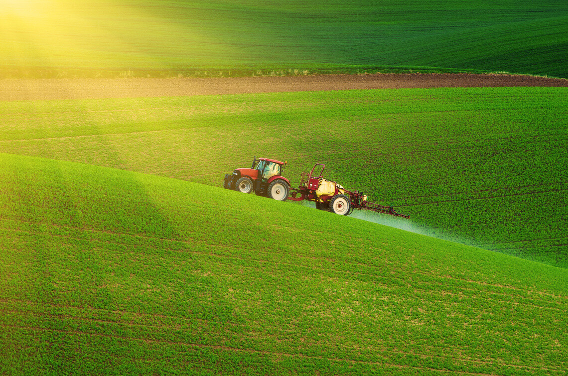Farm machinery spraying insecticide to the green field, agricultural natural seasonal spring background