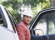 Construction worker getting out of the passenger seat of a white pickup truck