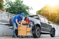 Delivery men unloading cardboard boxes from pickup truck