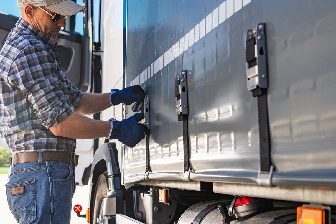 Man in hat securing cargo on a semi truck