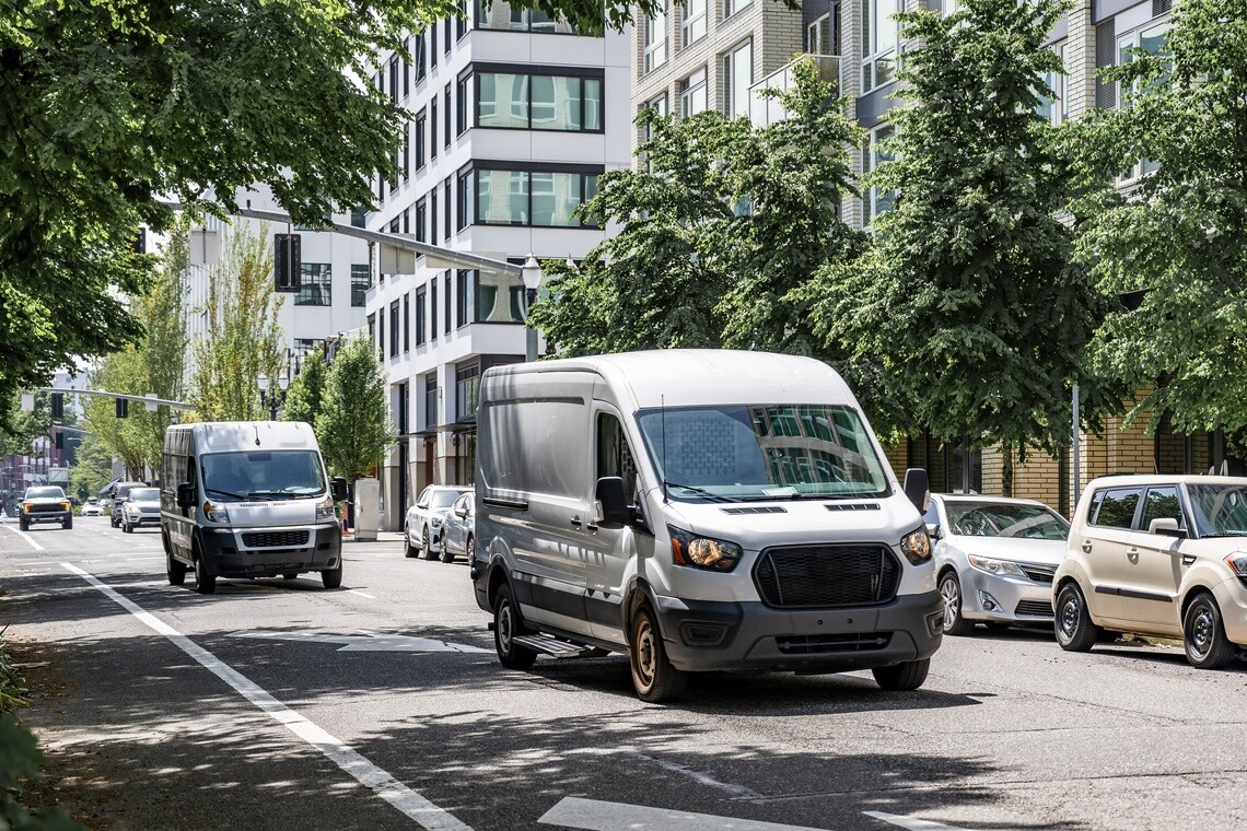 Two white delivery vans driving down city street