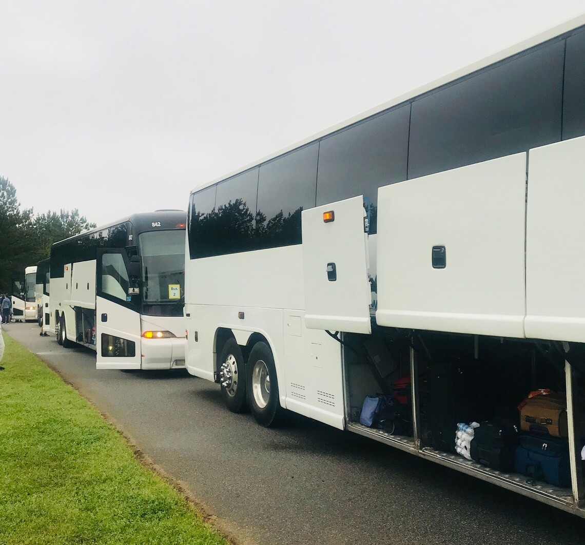 two white coaches parked facing each other on the edge of a road