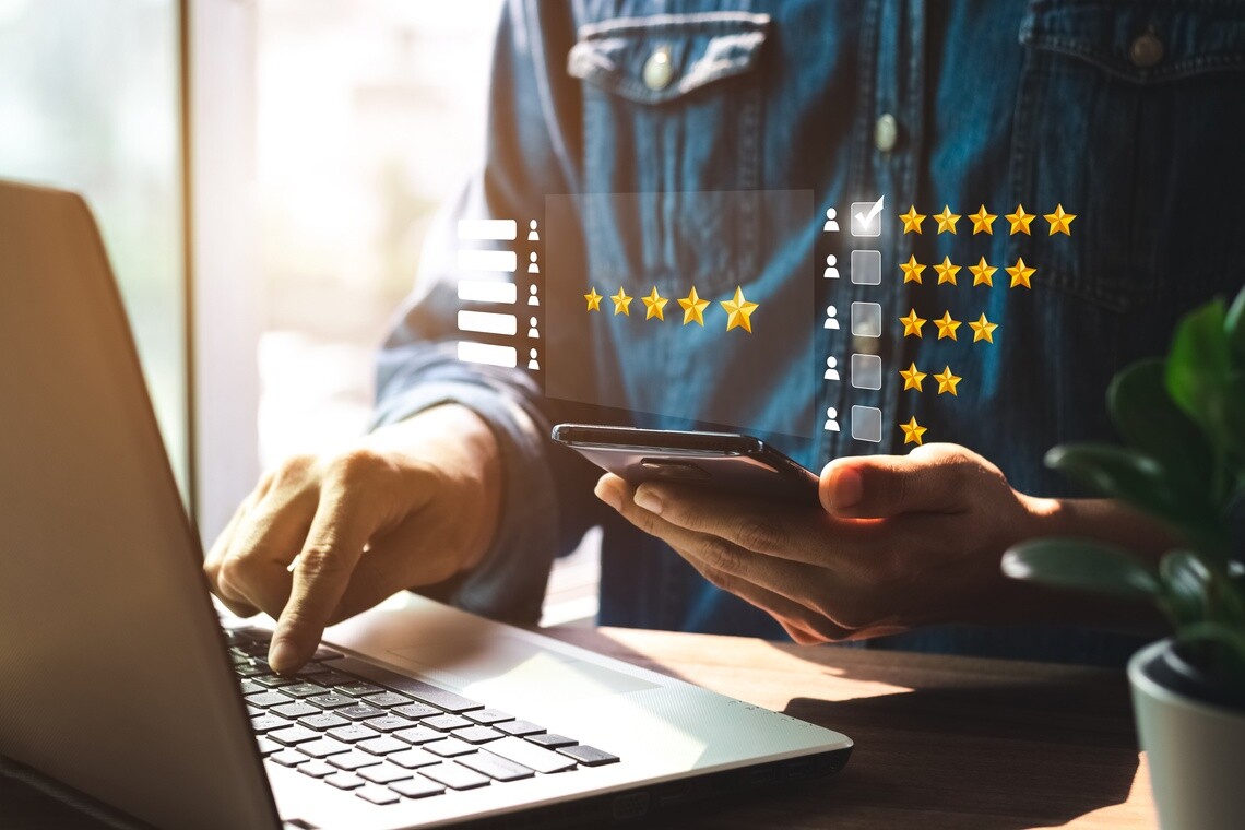 Une personne regardant les évaluations sur son téléphone et son ordinateur portatif