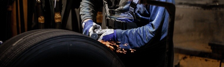 Man performing retread process on a tire with sparks flying