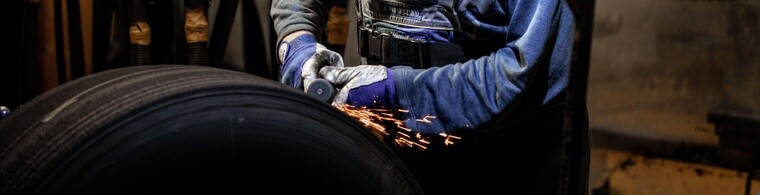 Man performing retread process on a tire with sparks flying