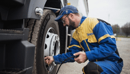 Homme en combinaison mécanique Michelin jaune et bleu mettant de l’air dans le pneu d’un semi-camion