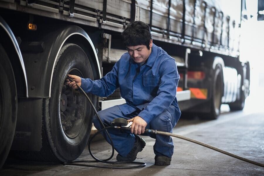 Technician checking the pressure of the tyre on a heavy truck vehicle