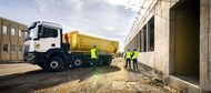 Heavy-duty dump truck with large commercial tires at a construction site with workers nearby