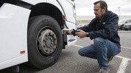 A man with a handheld device next to a bus tire scanning the RFID