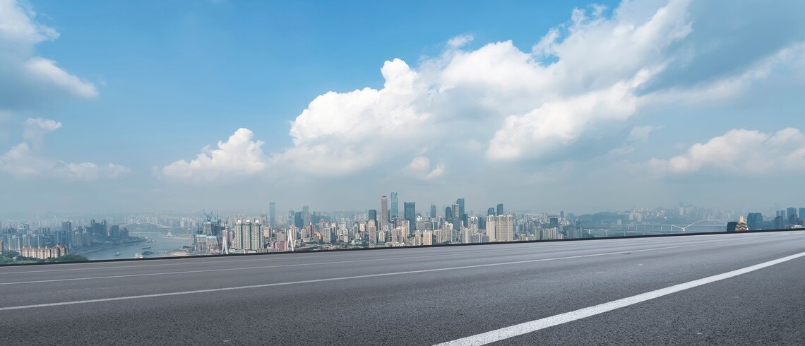 Skyline of city against blue cloudy sky and highway in the foreground