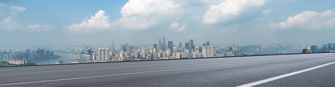 Skyline of city against blue cloudy sky and highway in the foreground