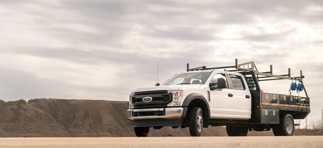 white regional utility work truck parked in a dirt lot with hills behind it