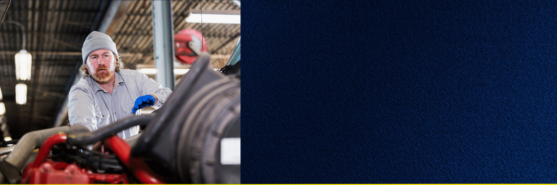 Technician working on engine of a semi truck with blue texture on right side