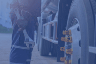 Technician standing by a semi tire holding a wrench