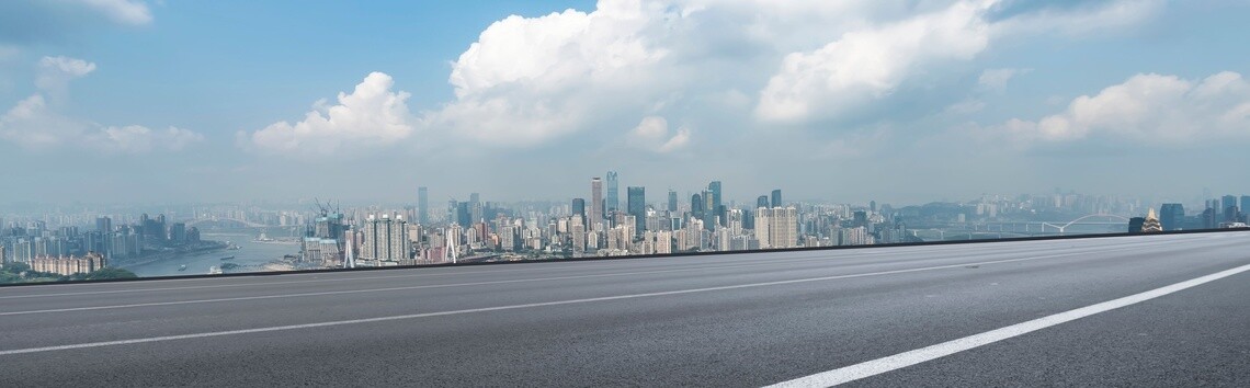 City skyline in background against blue sky with clouds and highway in foreground