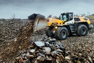 A yellow wheel loader equipped with Michelin Xtra Defend E4/L4 tires working in a quarry environment with rock piles.
