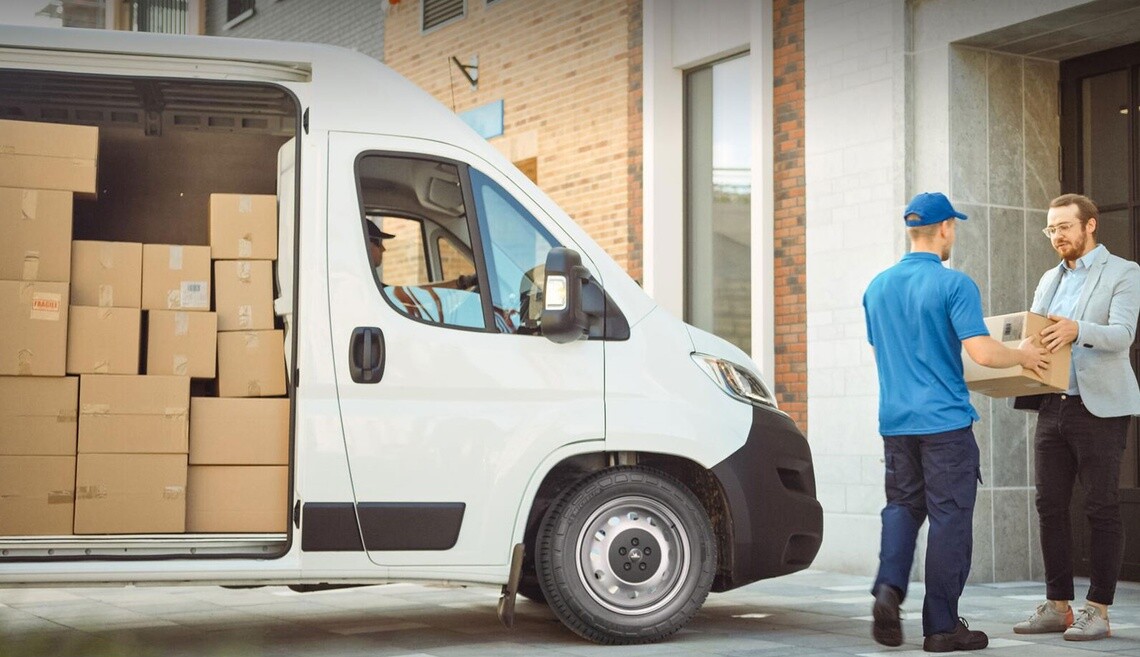 Courier handing a package to a customer in front of a delivery van