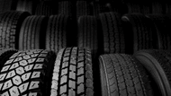 Close-up of multiple commercial tires featuring different tread patterns, with additional tires displayed in the background.