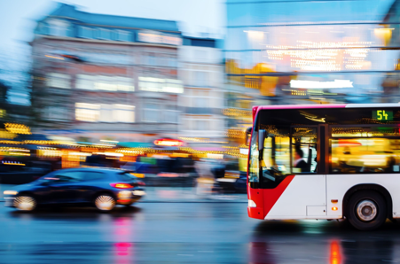 Urban bus driving on a wet city street at night