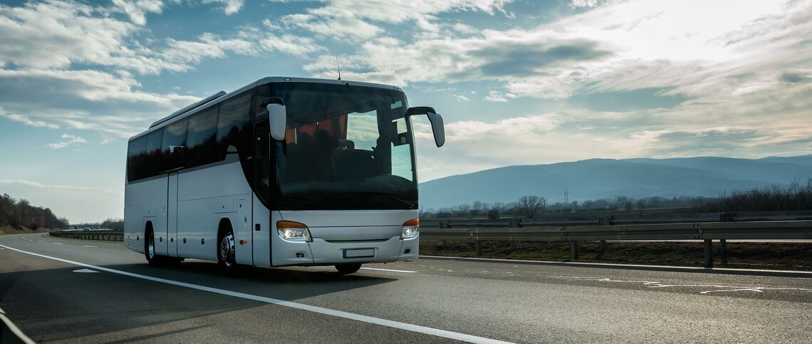 Motor coach on empty highway with clouds and blue sky overhead
