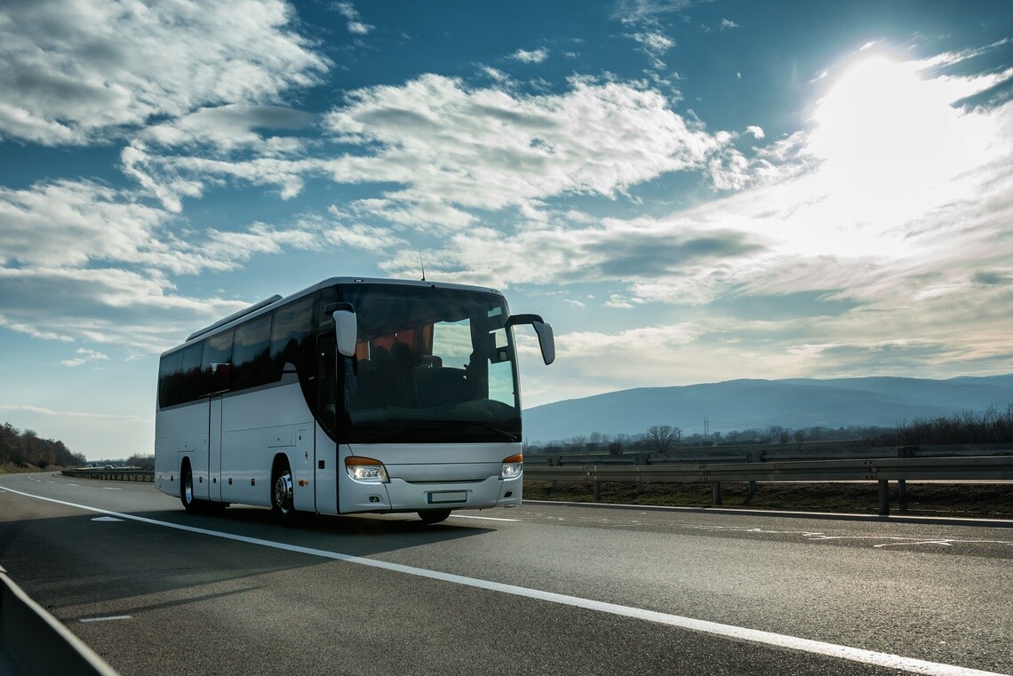 Motor coach on empty highway with clouds and blue sky overhead