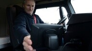 Commercial truck driver using an in-cab digital device to monitor fleet operations, connected technology, and route performance.
