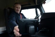 Commercial truck driver using an in-cab digital device to monitor fleet operations, connected technology, and route performance.