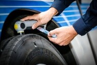 Technician using a digital tire inspection tool and mobile device to support commercial fleet maintenance and connected tire services.