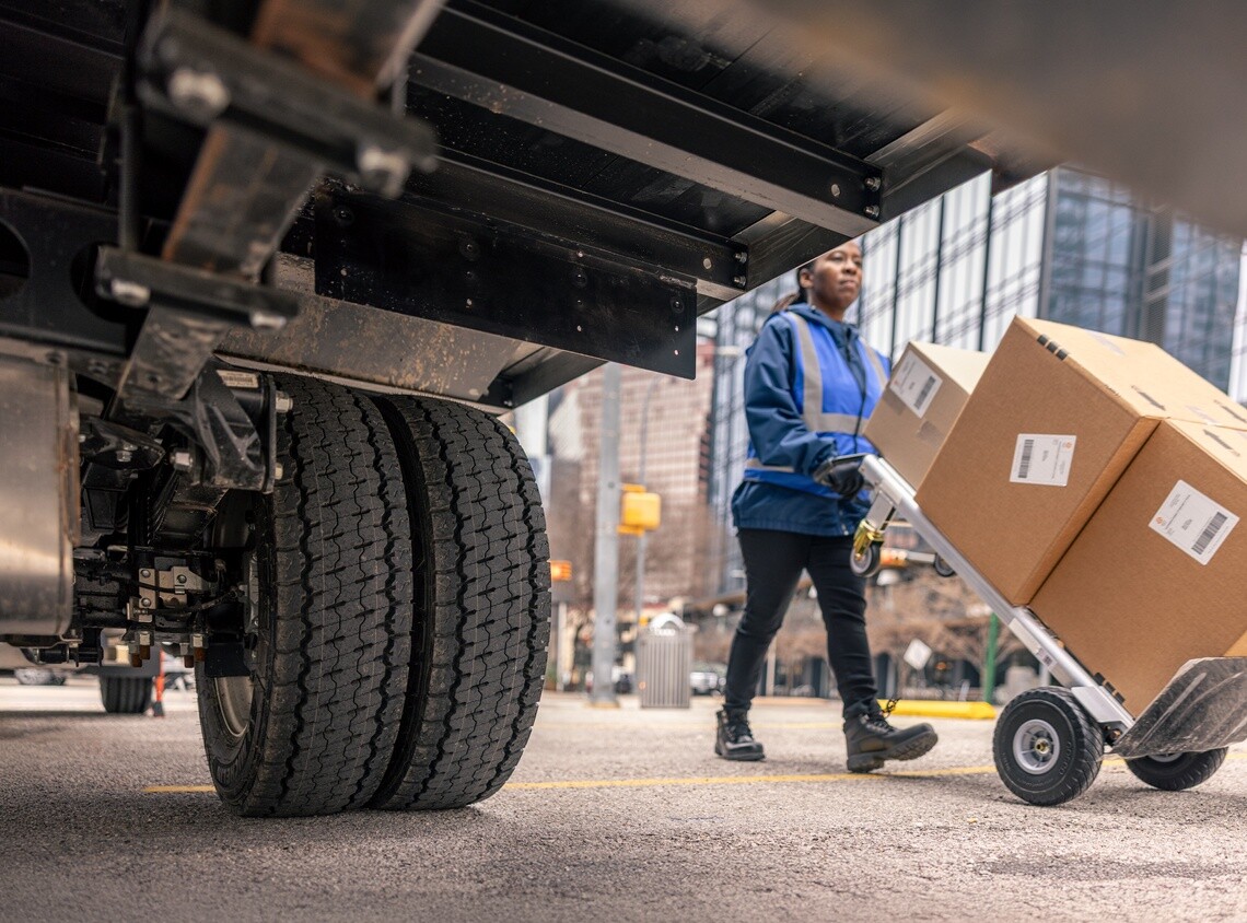 Delivery driver unloading commercial freight from a box truck equipped with Michelin Agilis tires in an urban fleet environment.