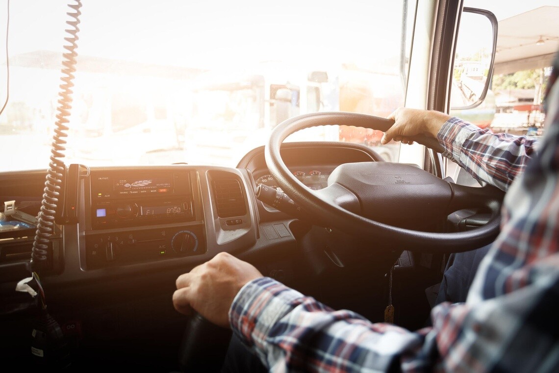Truck driver keeps driving with one hands and change gears,The man Behind Semi Truck Steering Wheel,spot focus.