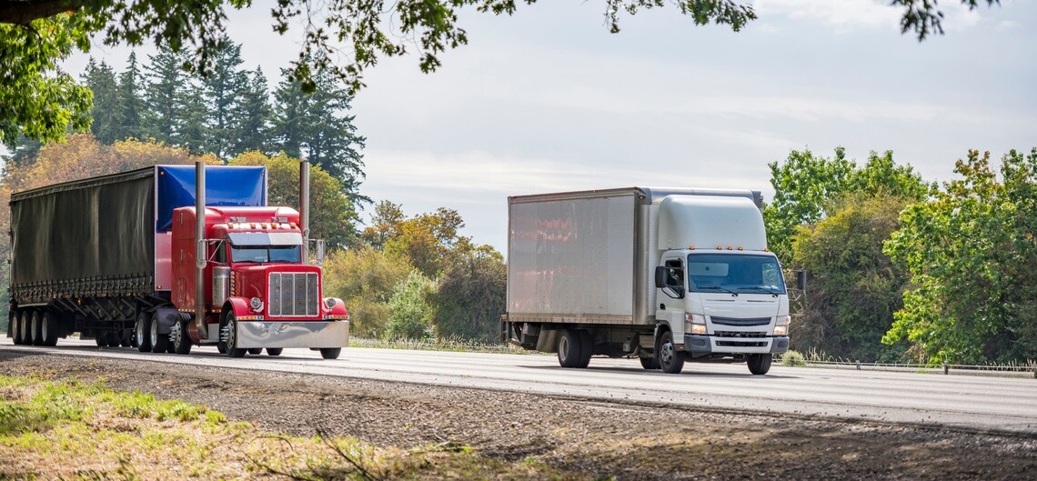 Semi truck and box truck transporting freight on a commercial roadway
