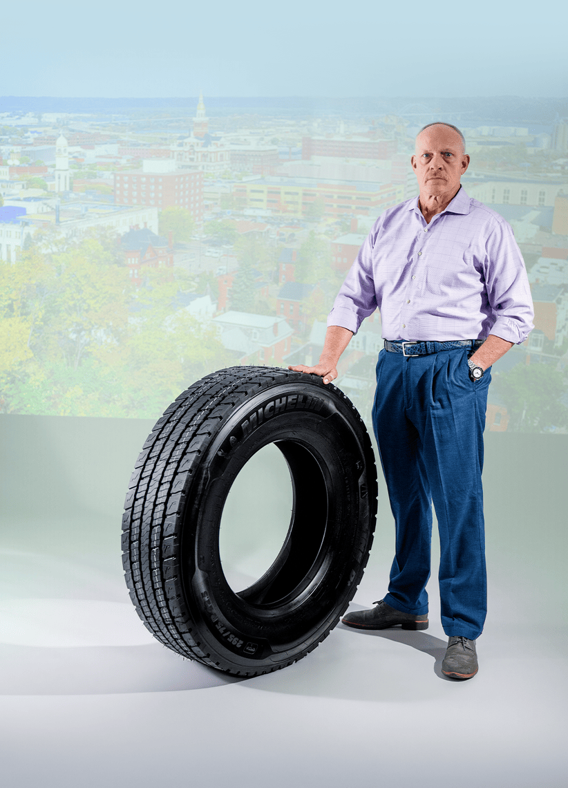 Fred Staugh, Chief Maintenance Officer at Hirschbach Motor Lines, standing beside a Michelin commercial truck tire as part of Michelin's It's More Than a Tire campaign.