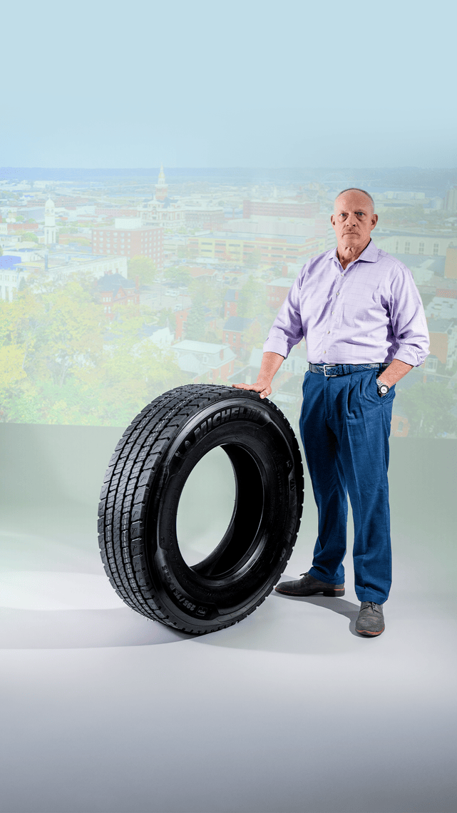 Fred Staugh, Chief Maintenance Officer at Hirschbach Motor Lines, standing beside a Michelin commercial truck tire as part of Michelin's It's More Than a Tire campaign.